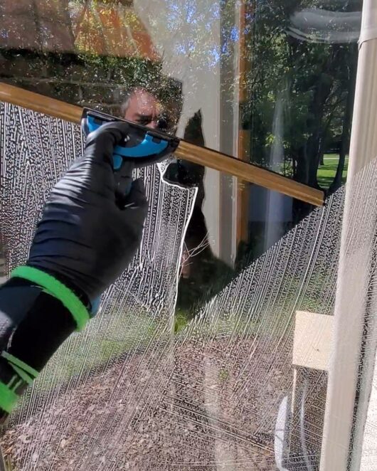 reflection of window cleaning technician using squeegee on window in Columbus Ohio