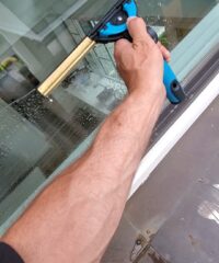 an arm squeegeeing a second story window