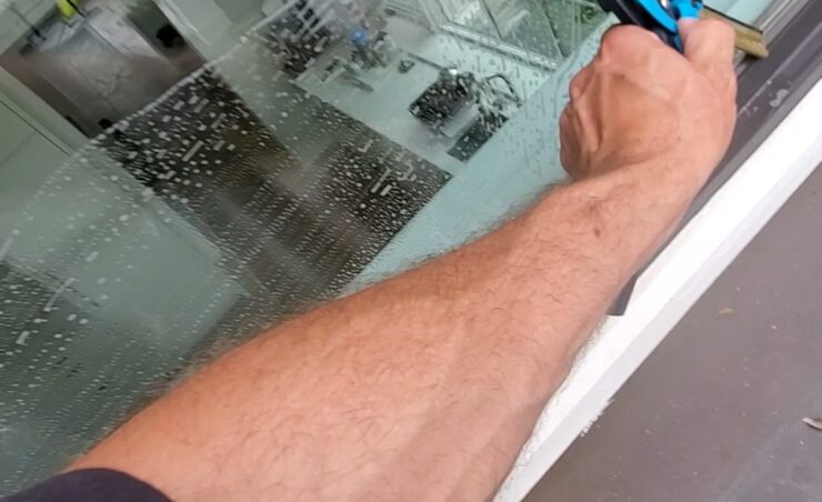 window cleaning technician arm squeegeeing a second story window