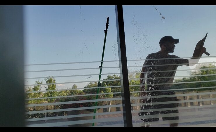 window cleaning technician using a squeegee on a large window