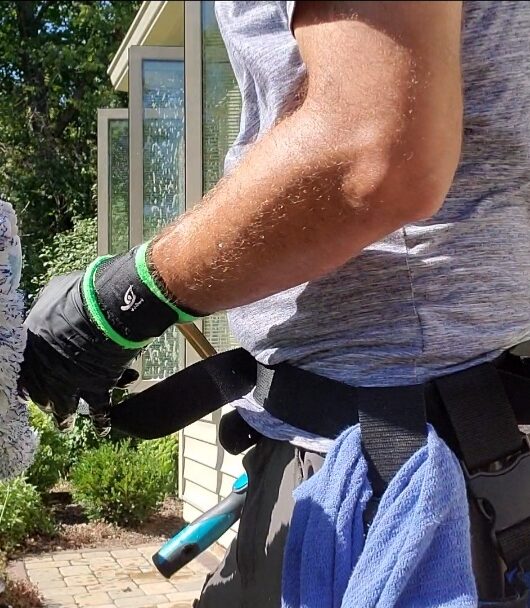 window cleaning technician standing next to house holding window scrubber